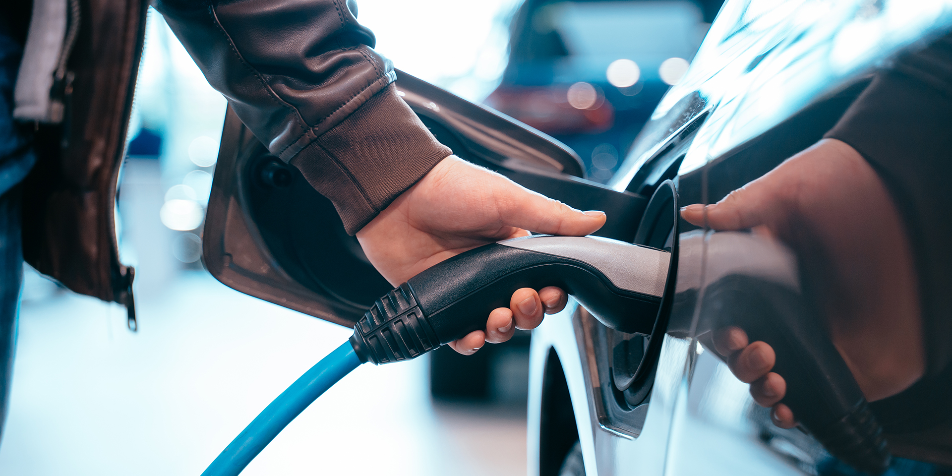 Hand steckt Ladestecker in eine elektrische Fahrzeug-Ladesäule