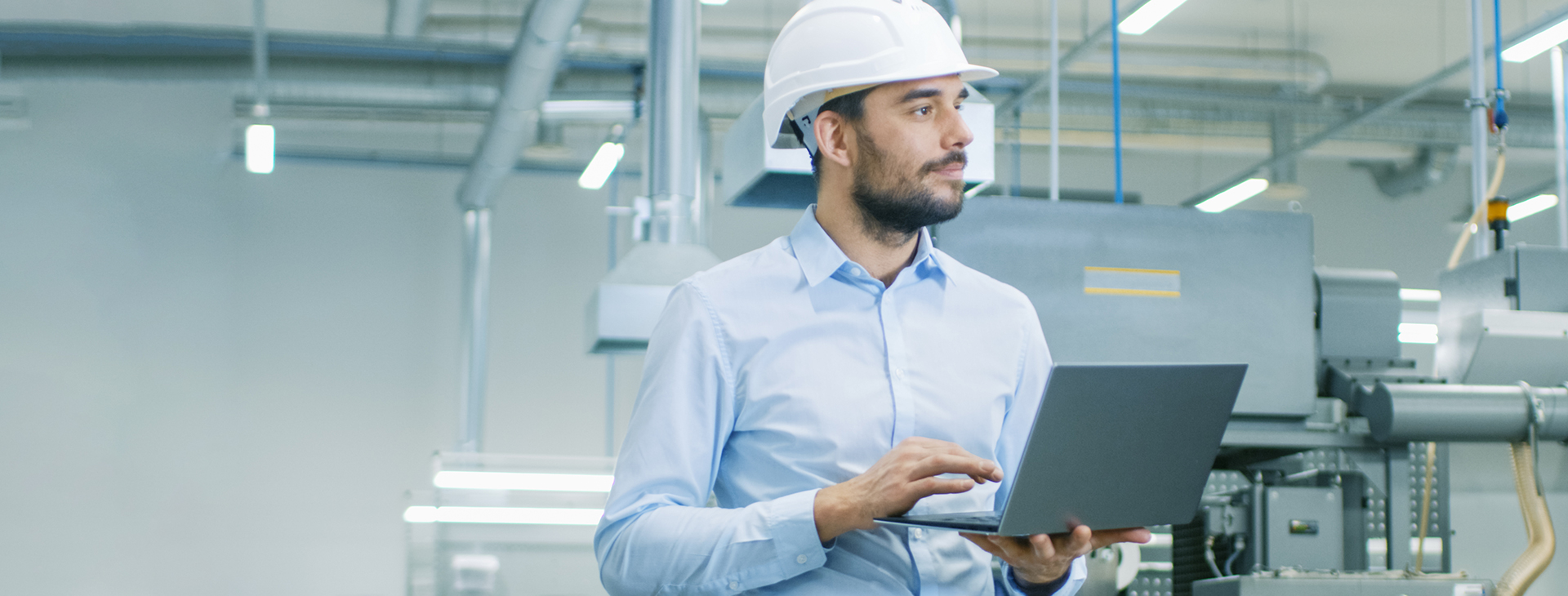 Ingenieur mit Schutzhelm und Laptop in einer Industrieanlage in Bochum