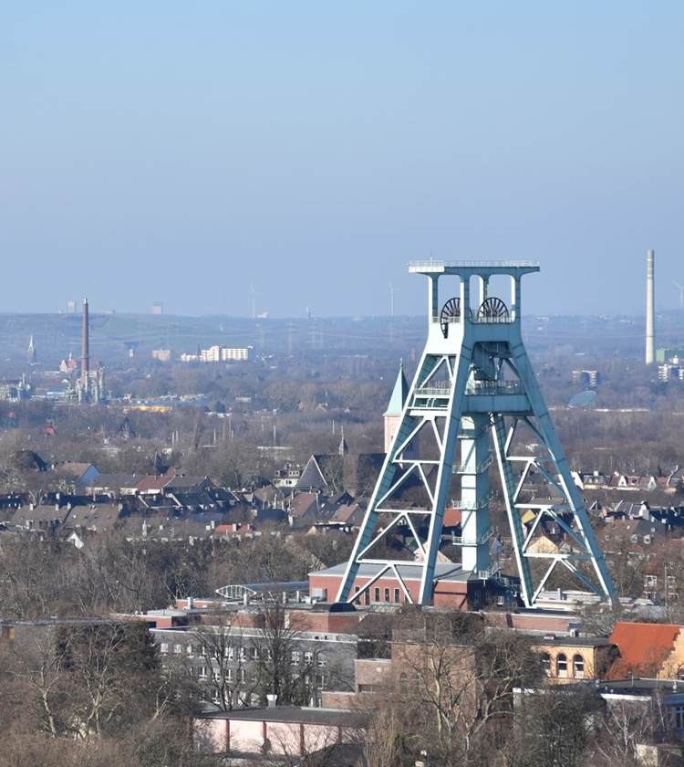 Förderturm eines Bergwerks vor einer städtischen Landschaft in Bochum