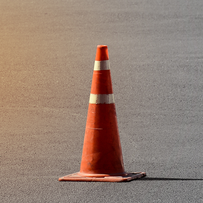 Oranger Verkehrshütchen auf Asphaltboden